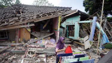 A woman dries her laundry in front of her home shortly after the quake in West Lombok.