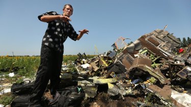 Donetsk People's Republic sniper Eugene Lukovkin, aged 30, stands among the pilots' bags at one of the sites where he witnessed the front section of Malaysian flight MH17 crashing.