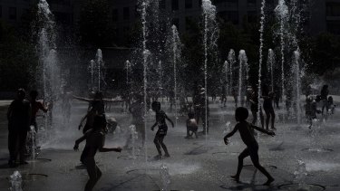Children play at a fountain in a park in Paris. Many school closed due to unprecedented heat,