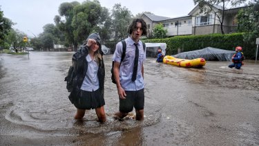 Student trudge through floodwater on Macpherson Street, Warriewood.