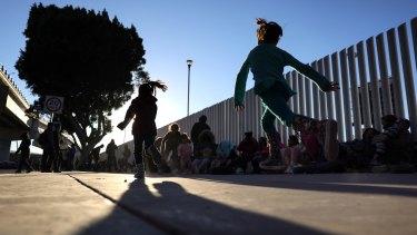 Children play as people who are seeking asylum in the United States are gathered outside the El Chaparral border crossing in Tijuana, Mexico. 