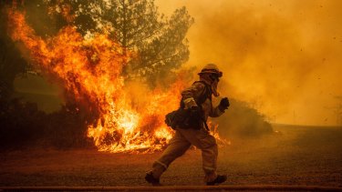 A firefighter runs while trying to save a home as a wildfire tears through Lakeport, California.
