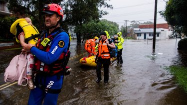 SES personnel help evacuate mums and their children from Guardian Childcare on Waine St, Manly due to flood waters. 