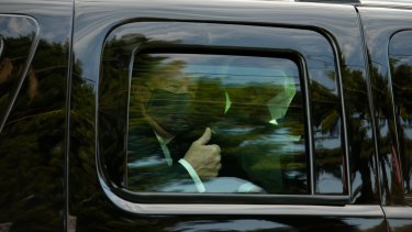 President Donald Trump gives a thumbs up as he is driven in a motorcade past supporters outside of Walter Reed National Military Medical Centre.