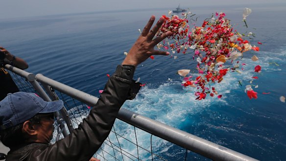 A relative sprinkles flowers for the victims of the crashed Lion Air flight 610 from an Indonesia Navy ship in the waters where the plane is believed to have crashed.