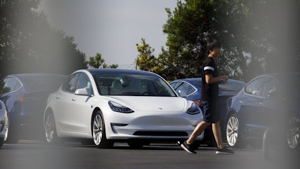 A person walks past a Tesla electric vehicle at the company's delivery center in Marina Del Rey, California.