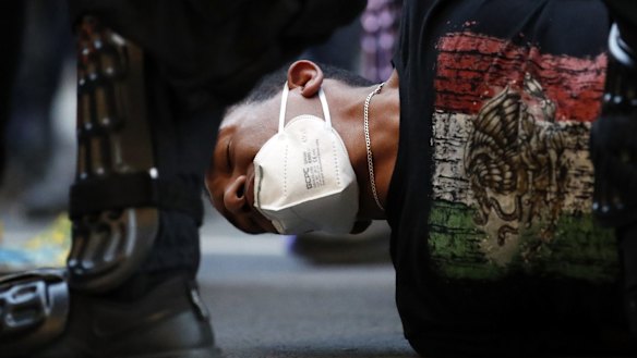 A demonstrator is taken into custody near the White House after a curfew took effect during a protest over the death of George Floyd.