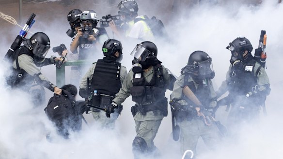 Police in riot gear move through a cloud of smoke as they detain a protester at the Hong Kong Polytechnic University.