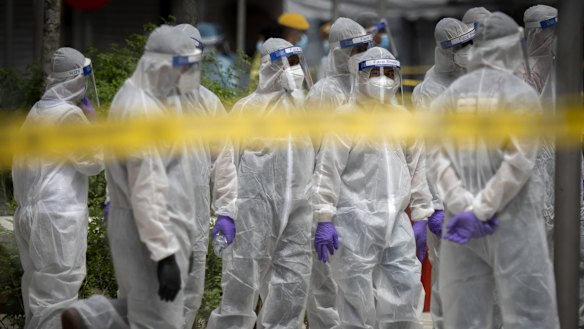 Immigration officers wearing protection suits in a locked-down area.