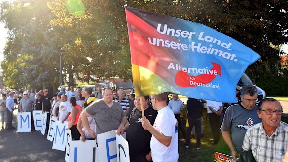 AfD supporters hold posters "Merkel must go" and a flag "Our country, our homeland " last year.