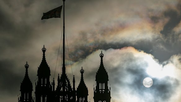 The sun breaks through clouds behind the Houses of Parliament in London.