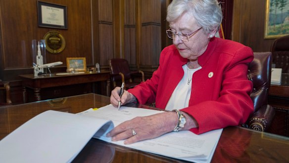 Alabama Governor Kay Ivey signing a bill that virtually outlaws abortion in the state.