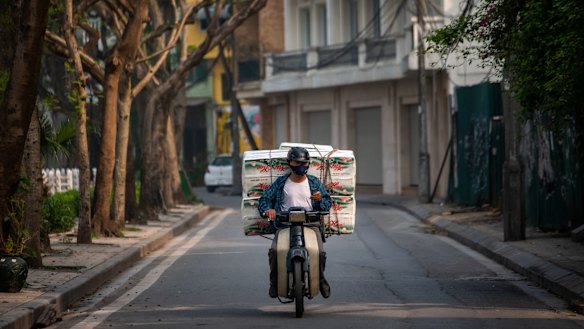 A delivery man with a load of toilet paper rides past the quarantined area of Truc Bach Street in Hanoi, Vietnam. 