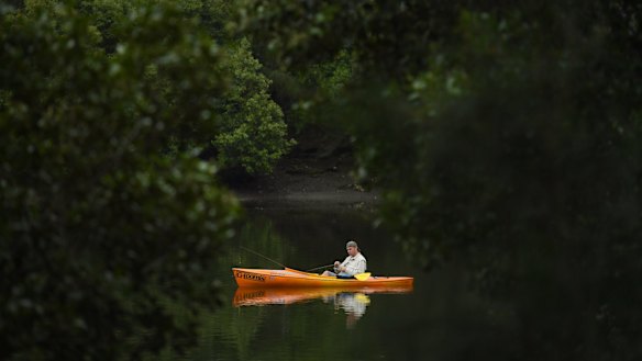 A man fishing from his small boat on the Cooks River at Kendrick Park.