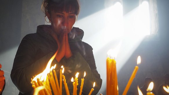 A woman lights candles inside a church of the Dadivank, an Armenian Apostolic Church monastery dating to the 9th century, as ethnic Armenians leave the separatist region of Nagorno-Karabakh to Armenia.