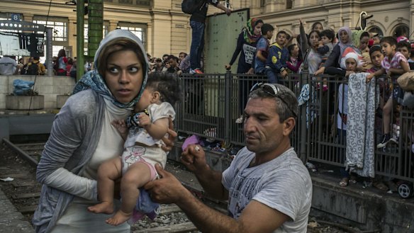 A migrant family gathers with a few hundred others waiting for a train to Germany at the Keleti train station in Budapest, September 2015.