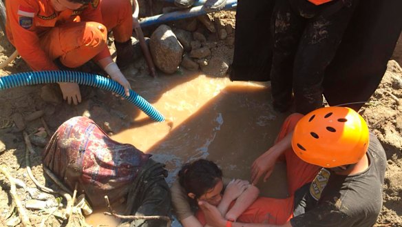 An Indonesian rescue team evacuates a women from damage following earthquakes and a tsunami in Palu, Central Sulawesi, Indonesia, on Sunday.
