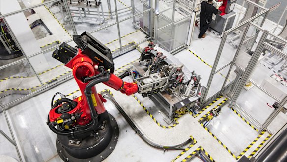 A welding robot and an employee at Tesla's California assembly plant.