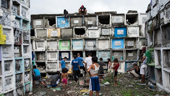 Shanty dwellers living inside the cemetery look at bodies being buried in Manila, Philippines.