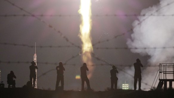 People watch a Soyuz-FG rocket booster carrying a new crew to the International Space Station blast off at the Russian leased Baikonur cosmodrome in Kazakhstan.