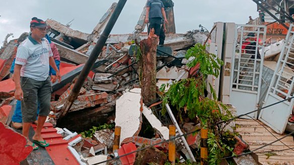 Residents inspect earthquake-damaged houses in Mamuju, West Sulawesi, on Friday.
