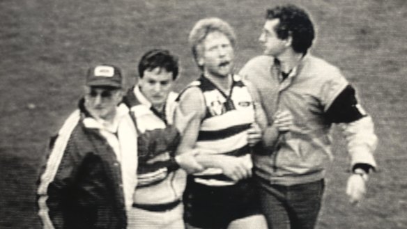 A distressed Neville Bruns is helped from the field in 1985.