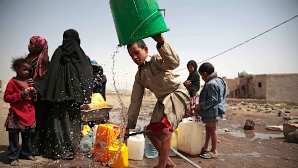 A boy rinses a bucket as he and others collect water in war-torn Yemen. 