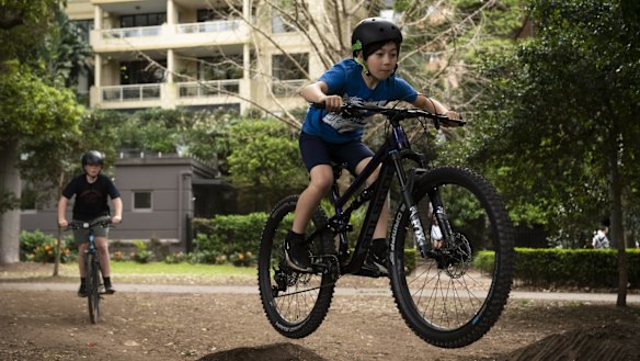 A group of kids having fun jumping their bikes in Rushcutters Bay Park.
