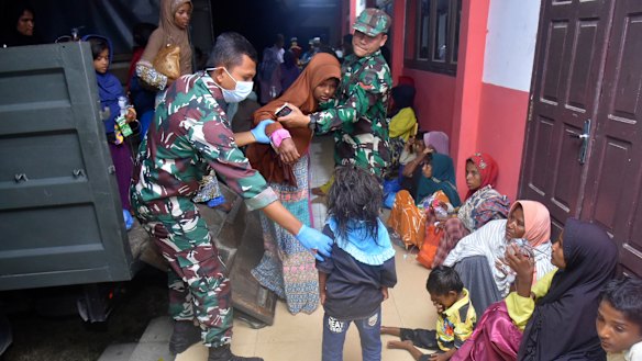 Indonesian soldiers help Rohingya women and children at a temporary shelter after their boat landed in Pidie, Aceh province in December.