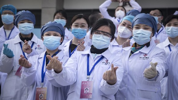 Medical professionals pose for photos as the last batch of COVID-19 patients are discharged from Wuchang Fang Cang makeshift hospital in Wuhan in March.
