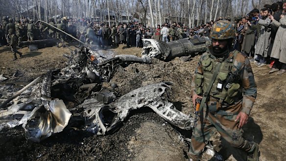 An Indian army solider walks past the wreckage of an Indian aircraft after it crashed in the outskirts of Indian controlled Kashmir.