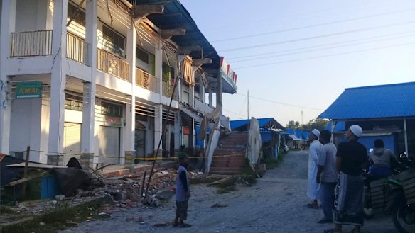 People survey a building partially damaged by earthquake in Poso, Central Sulawesi.