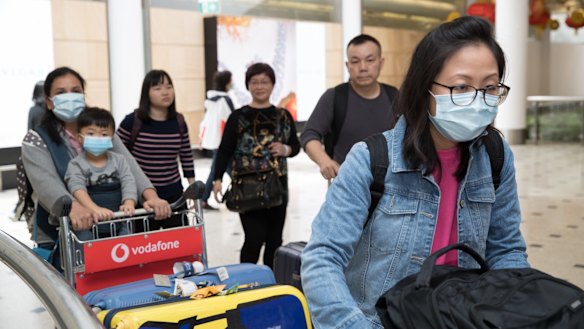 Passengers arrive at Sydney Airport wearing masks. 