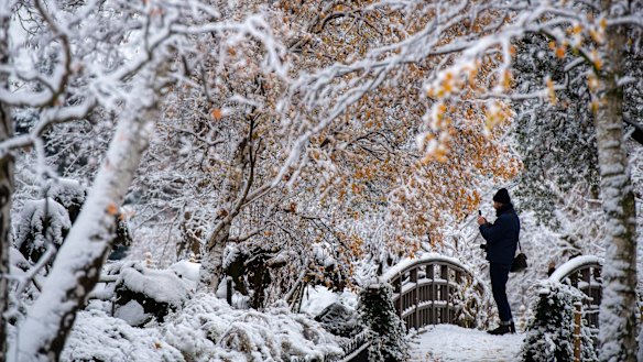 A visitor takes pictures of a snow covered Regent’s Park in London on Monday.