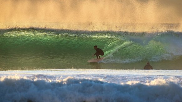 Surfers use the growing swell along the Sydney coast. 