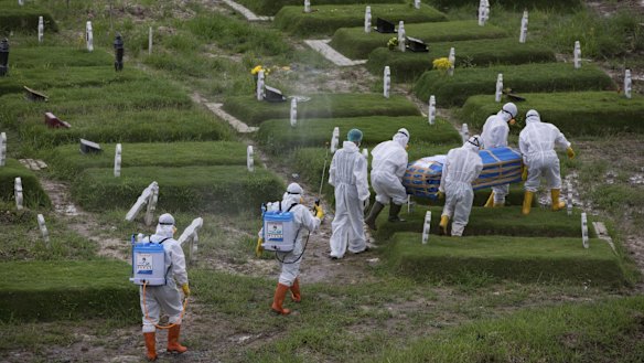 Workers in protective suits carry a coffin containing the body of someone who presumably died of the coronavirus for burial in Medan, North Sumatra, Indonesia.