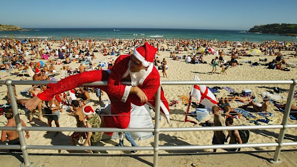 Santa Claus climbs down to the sand as crowds gather on Bondi Beach.