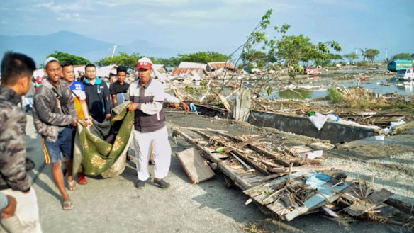 People carry the body of a tsunami victim in Palu.