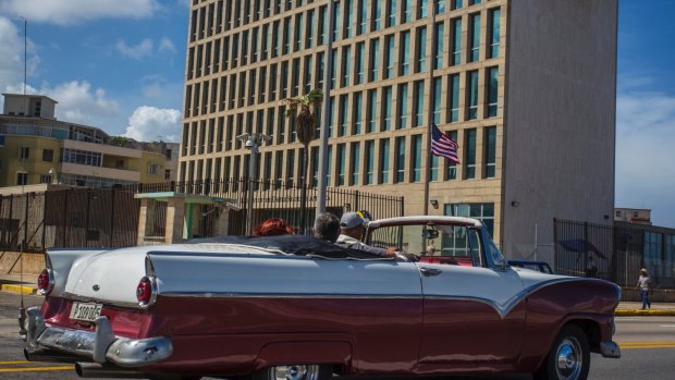 A classic convertible drives past the United States embassy in Havana, Cuba.