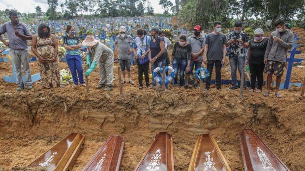 People wearing protective masks stand at the graves of their relatives at the Parque Taruma cemetery in Manaus, Brazil, during a mass burial of coronavirus victims. 