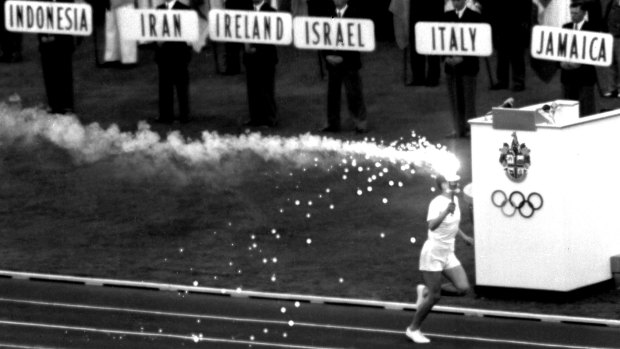 Ron Clarke runs into the MCG with the Olympic Torch during the opening ceremony.