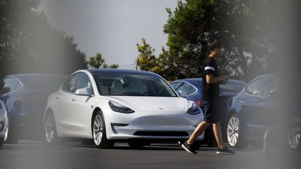A person walks past a Tesla electric vehicle at the company's delivery center in Marina Del Rey, California.