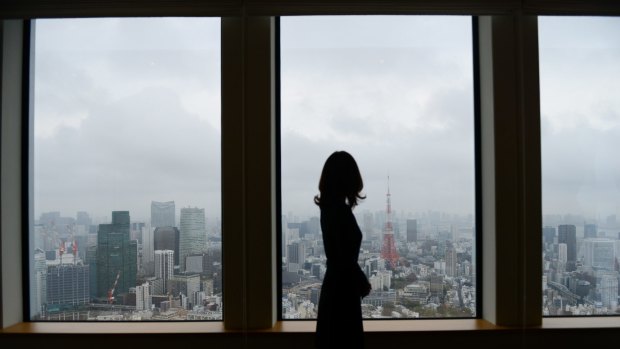 A woman looking out of a window of an office building in Tokyo. Prime Minister Shinzo Abe's government has tried to empower women in the workplace - with mixed success.
