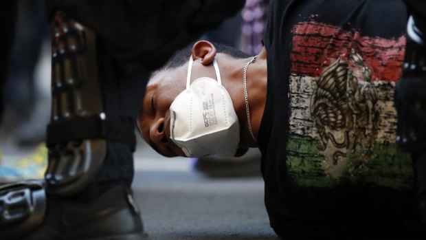 A demonstrator is taken into custody near the White House after a curfew took effect during a protest over the death of George Floyd.