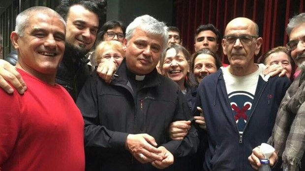 Cardinal Konrad Krajewski, centre, poses with activists and residents of an unused state-owned building in Rome.