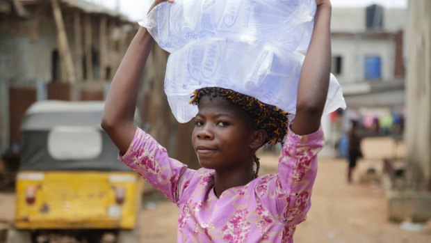 Ripe for development and loans. A woman carry bags of sachet water she bought on a street in Baruwa Lagos, Nigeria.