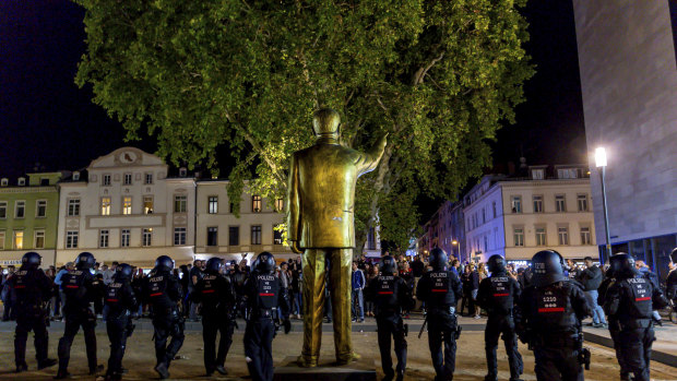 Police stand around the statue facing the crowd, before the controversial artwork was removed.