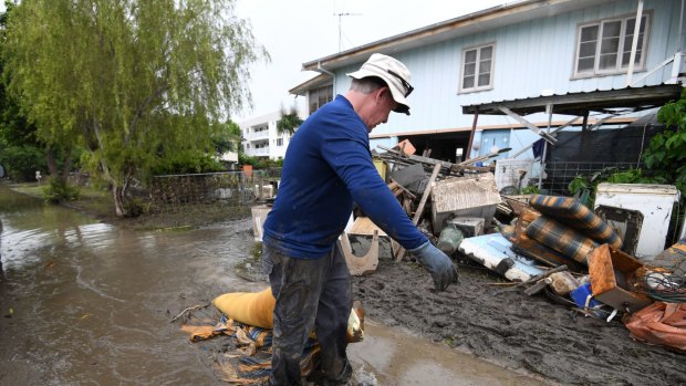 Chris Mitchell removes flood damaged items out of his father in-law's house in the suburb of Rosslea in  flood-affected Townsville