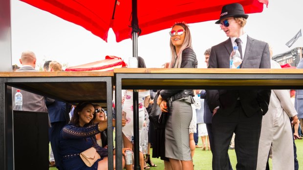 Katie and Lauren from Berwick take cover from the rain at the 2017 Caulfield Cup. 
