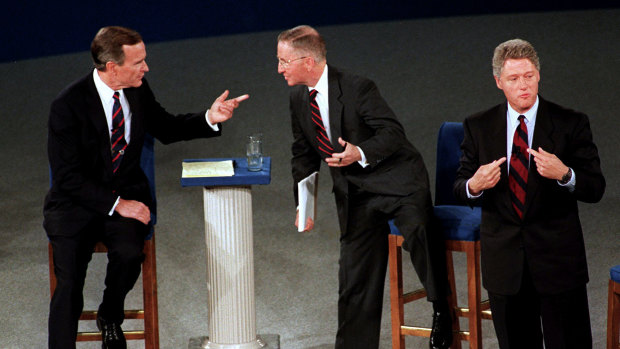 President George H.W. Bush, left, talks with independent candidate Ross Perot as Democratic candidate Bill Clinton stands aside at the end of their second presidential debate in 1992.  